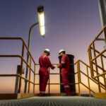 Two engineers working at dusk at Block 61 Gas Field in Oman